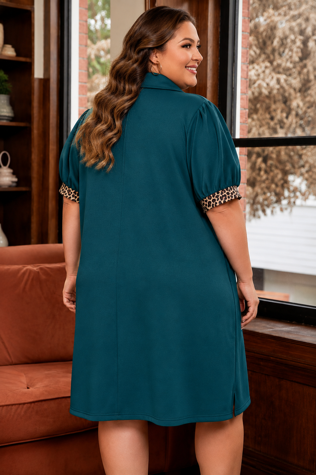 A woman wearing a teal short puff-sleeve dress with leopard-print trim on the sleeves, shown from the back in an indoor setting.