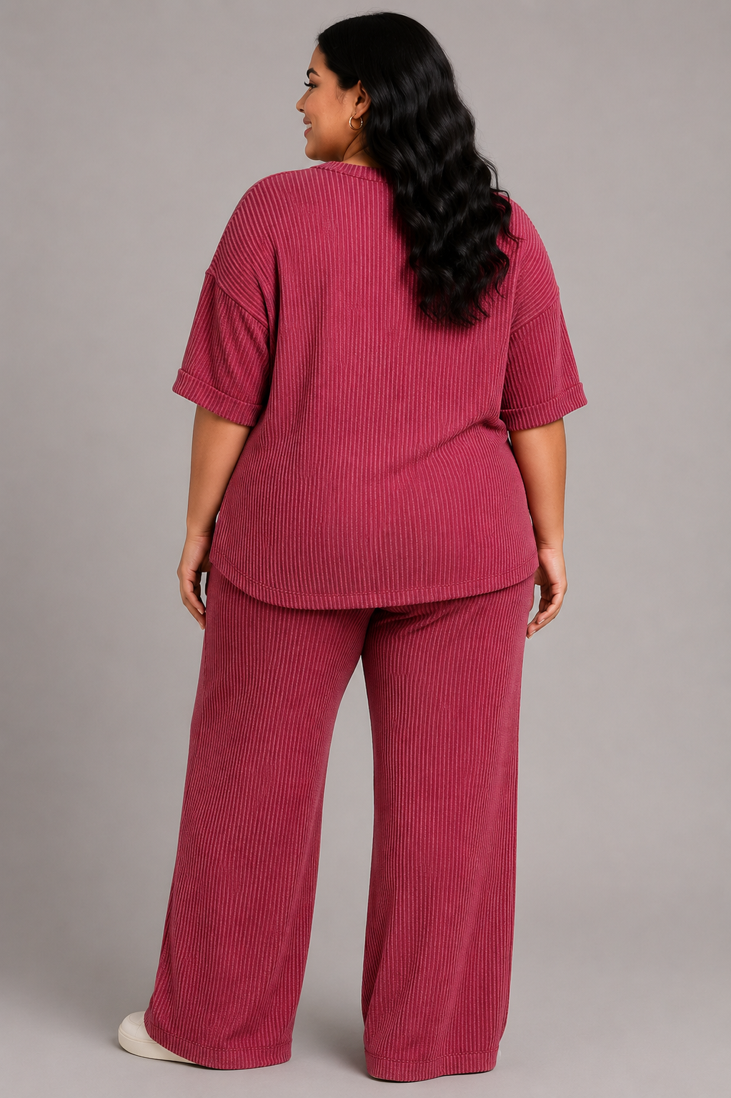 A woman shown from the back wearing a matching ribbed short-sleeve top and wide-leg pants set in a dusty rose pink color, photographed against a solid gray studio background.