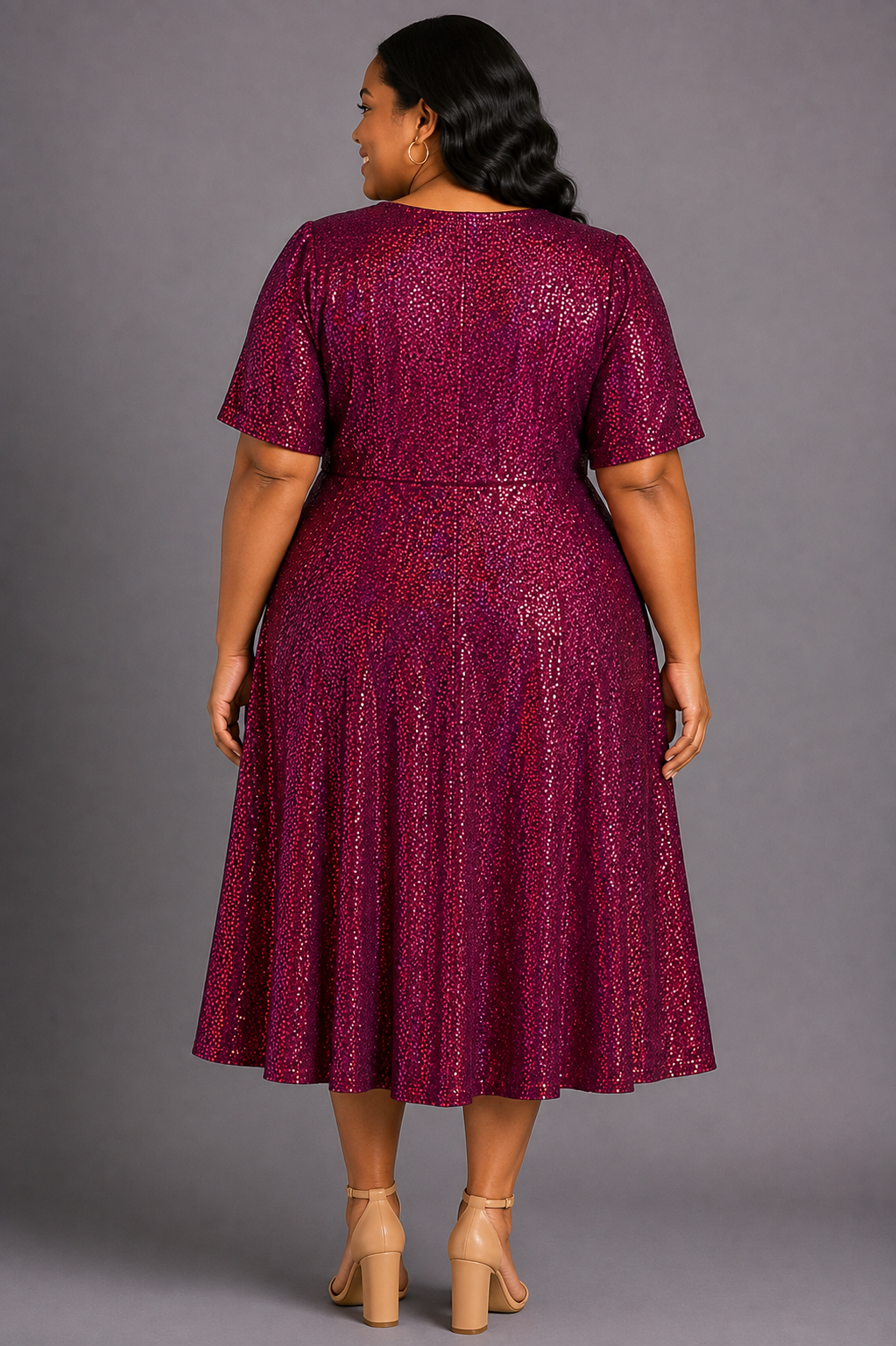 A woman shown from the back wearing a short-sleeve, knee-length dress with an allover textured pattern in deep burgundy and magenta tones, paired with beige high-heeled sandals, against a solid gray studio background.