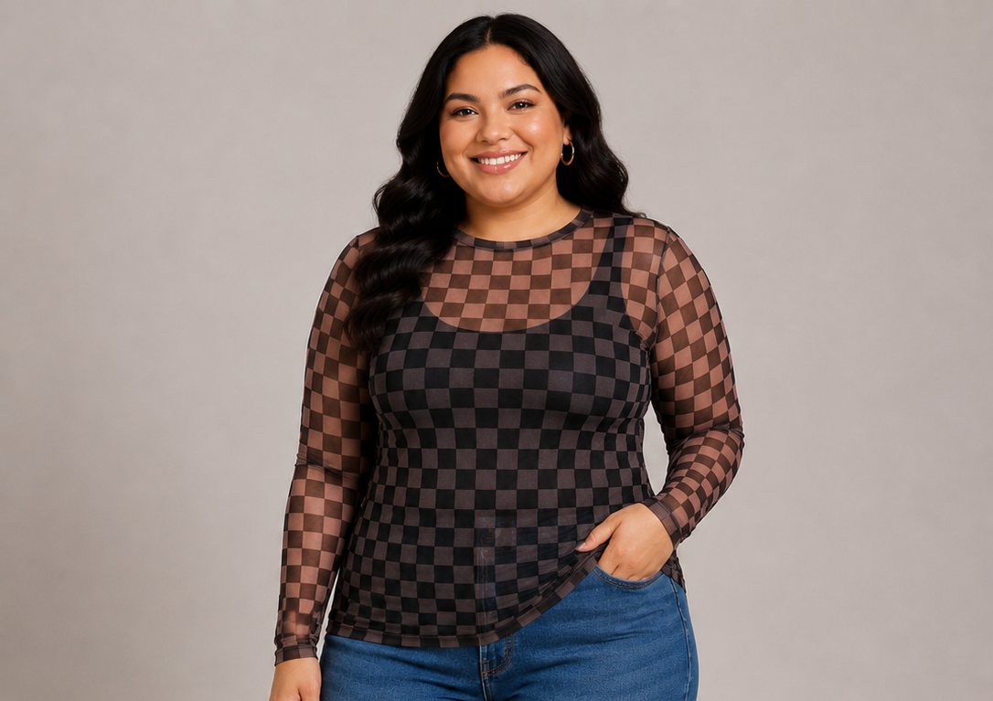A woman modeling a sheer long-sleeve top with a brown and black checkerboard pattern over a black tank top, paired with blue jeans, against a solid gray studio background.